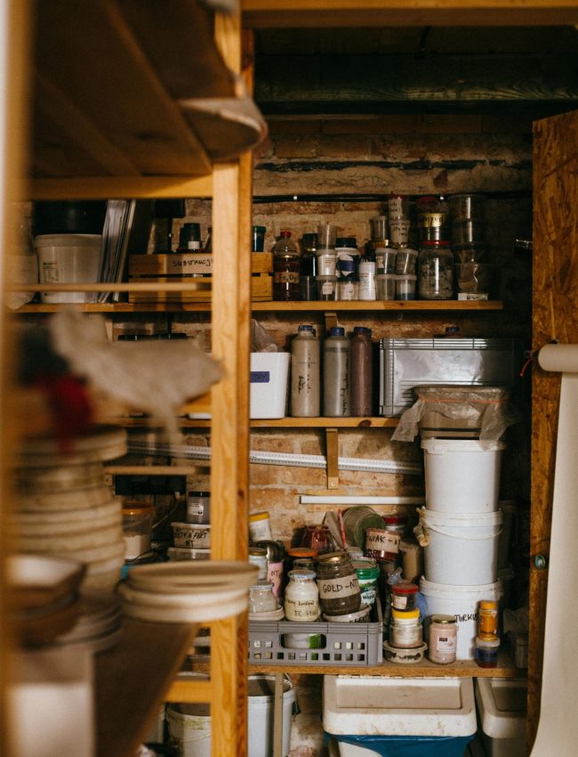 A well-organized storage room with wooden shelves filled with various containers and supplies.